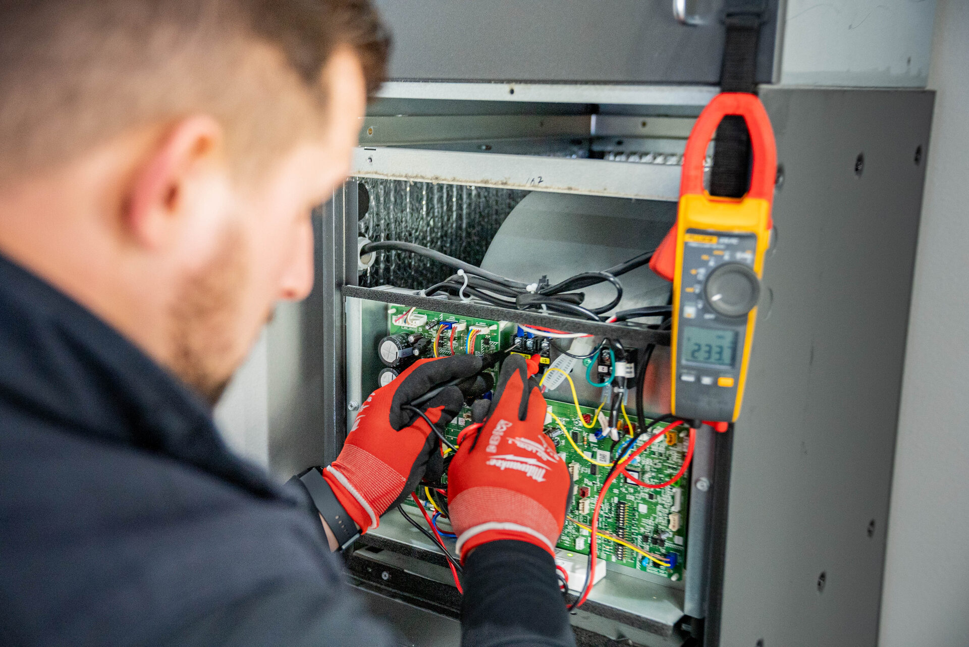 Product Air technician using a Fluke clamp meter to test an HVAC control board